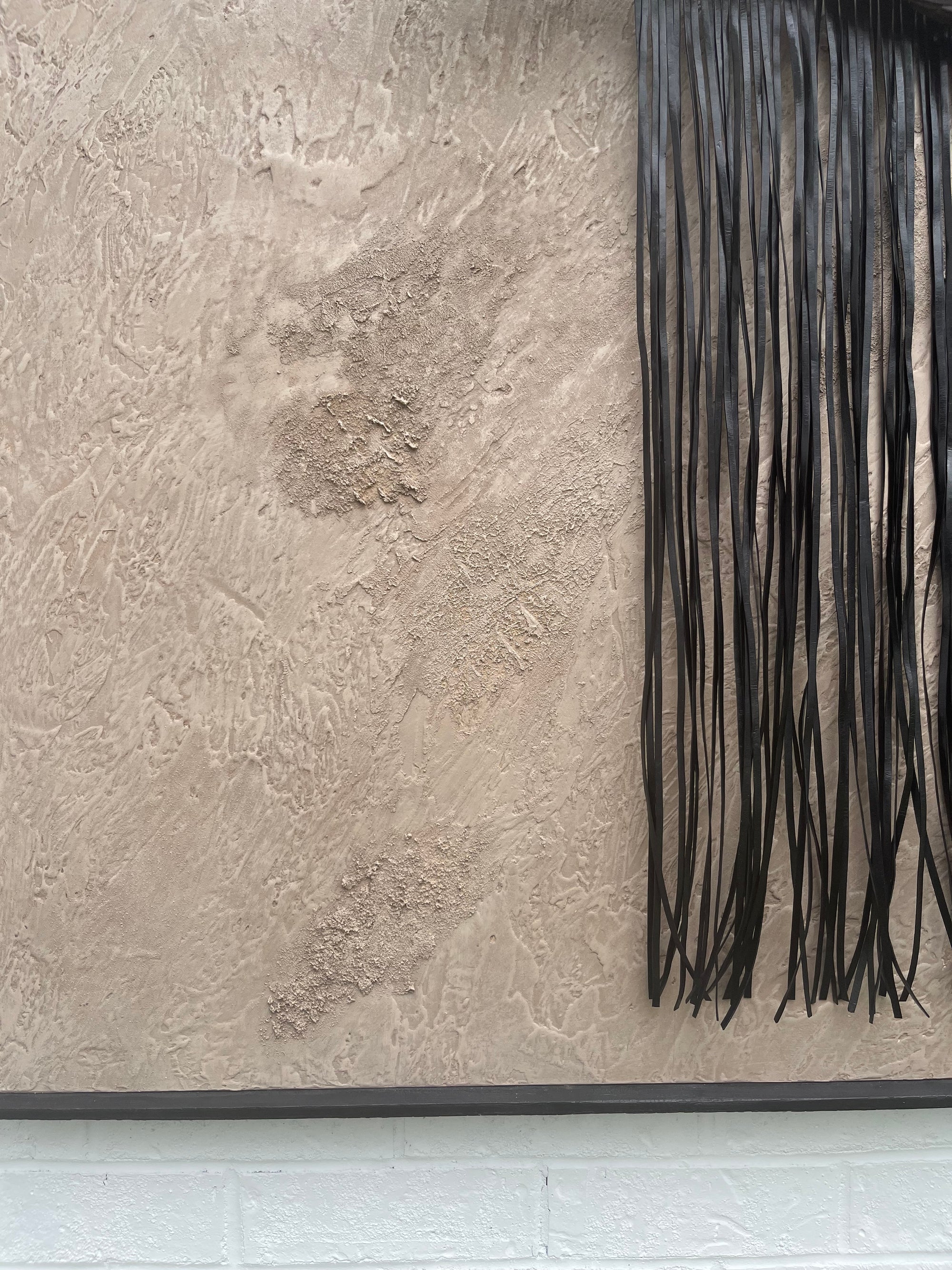 oversized textured painting sculpture detailed with concrete, plaster, ground pigments, ground crystals, detailed with a driftwood inserted loom embroidered with black leather yarn. in a shou sugi ban hand charred oak wood frame. 